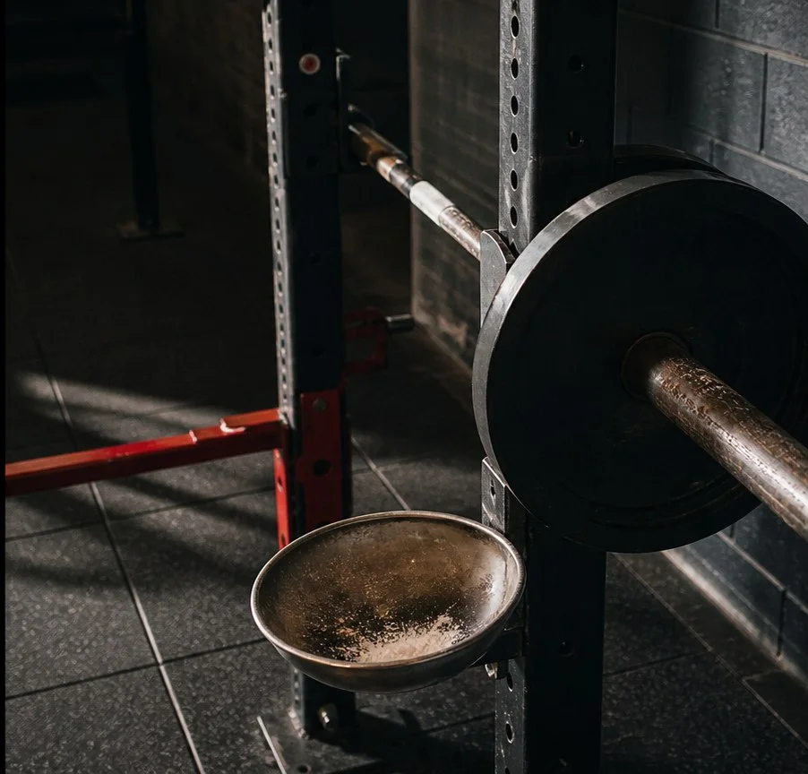 Boş bir squat kafesi: barbell rafında duruyor, yanında magnezyum kabı